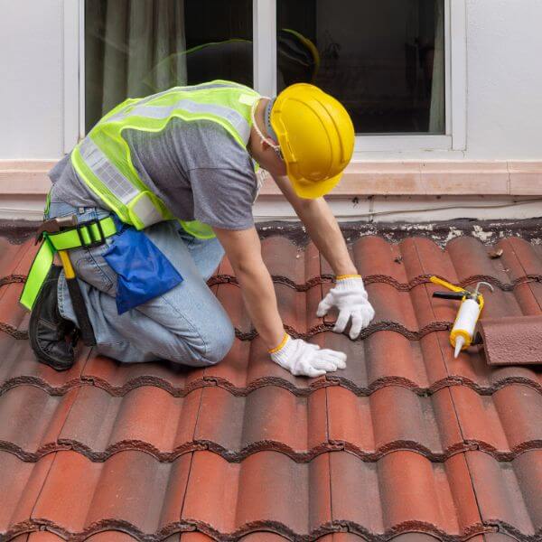 Roofer from Roofing Guys Sydney replacing damaged roof tiles during a full tile roof replacement on a residential property.