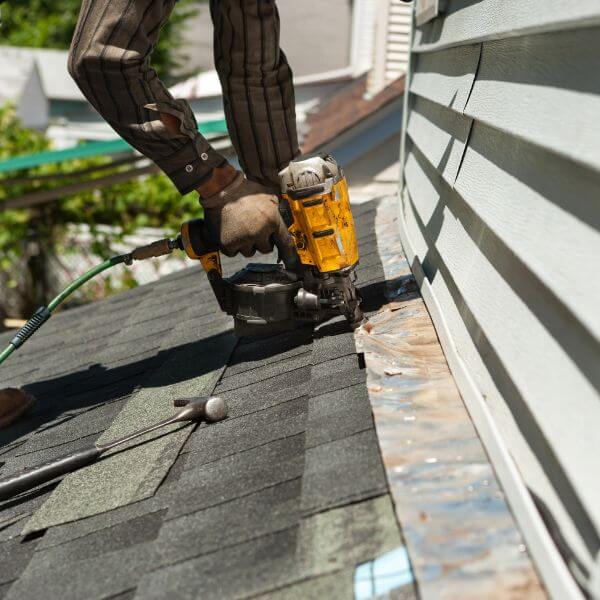 Roofer from Roofing Guys Sydney using nail gun to carry out emergency roof repairs on a storm-damaged roof in Sydney.