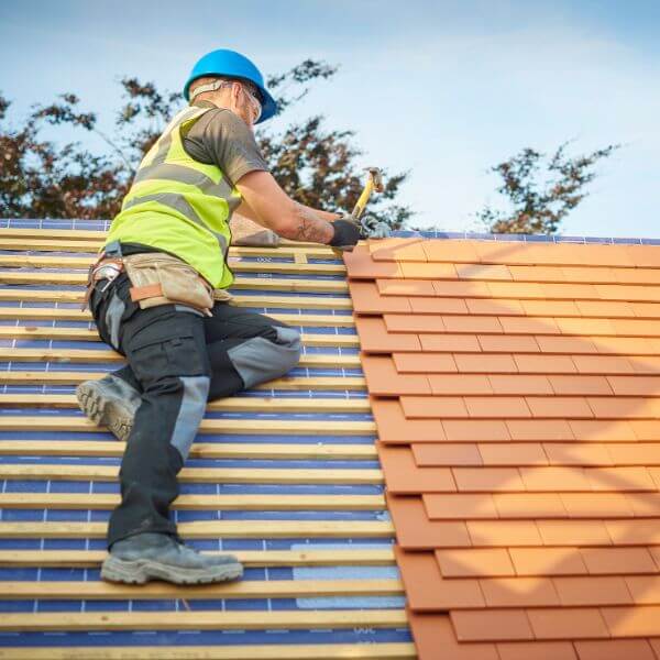 Roofing Guys Sydney roofer installing a new tiled roof with precision and care. We specialise in tile roof installations, re-roofing, repairs, and complete roof replacements across Sydney.