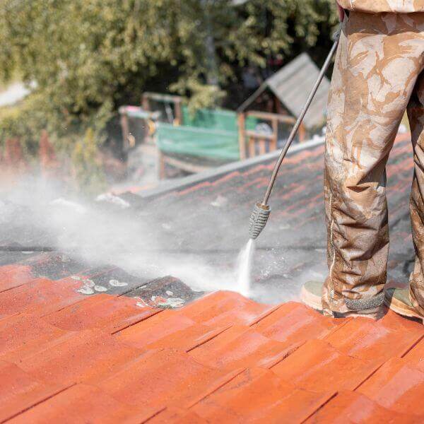 Roofing Guys Sydney team member pressure cleaning a tiled roof as part of a residential roof restoration in Sydney.