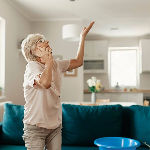 Sydney homeowner calling Roofing Guys Sydney for urgent roof leak detection after spotting a ceiling leak in her home.