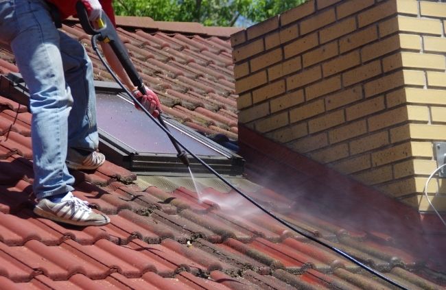 Close-up of roof cleaning service removing mould and debris from a tiled roof in Sydney Close-up of roof cleaning service removing mould and debris from a tiled roof in Sydney